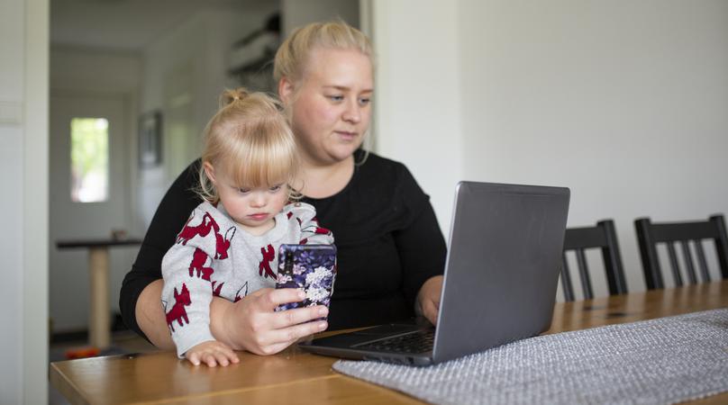 Mamma gör ärenden på datorn med dottern i knät