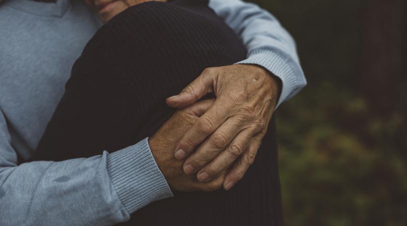 Äldre par kramas i skog