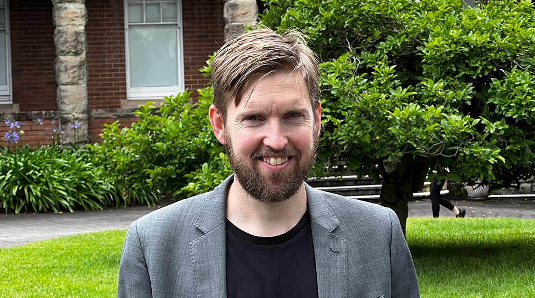 Thomas Lindow har skägg, brunt kort hår och ler med tänderna och solen i ögonen.