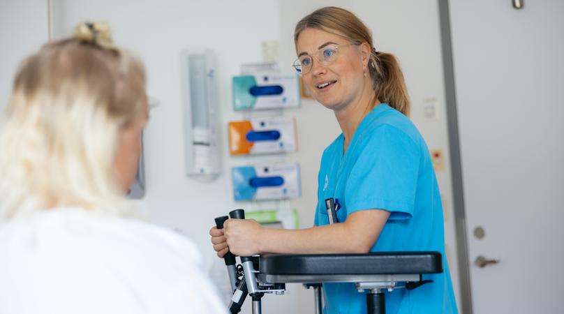 En fysioterapeut visar en patient gånghjälpmedel.