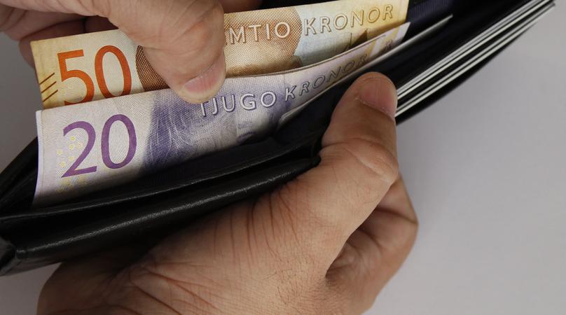 hands of a man holding swedish bills and a black leather wallet