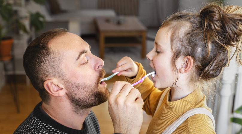 Pappa och barn borstar tänderna