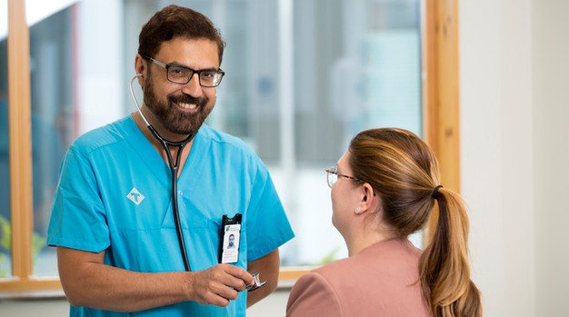En läkare lyssnar på hjärtat på en patient.