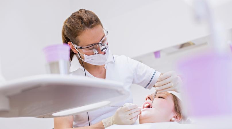 Dentist in dental clinic conducting dental examination on young woman