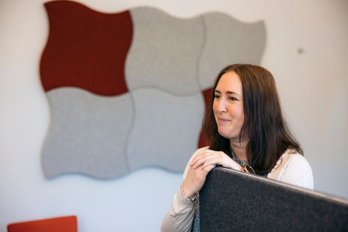 Therese står vid ett skrivbord och ler.