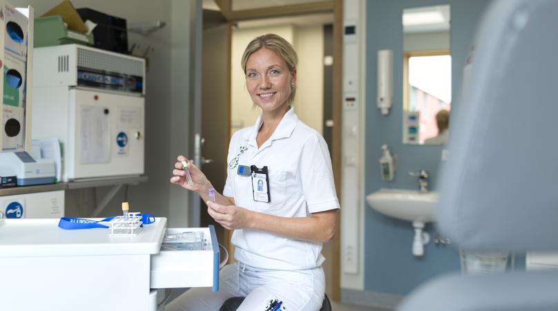 En undersköterska plockar fram provrör inför provtagning.