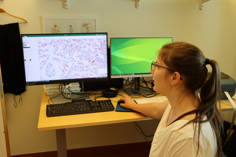 En kvinna sitter framför en datorskärm med lila fält på.