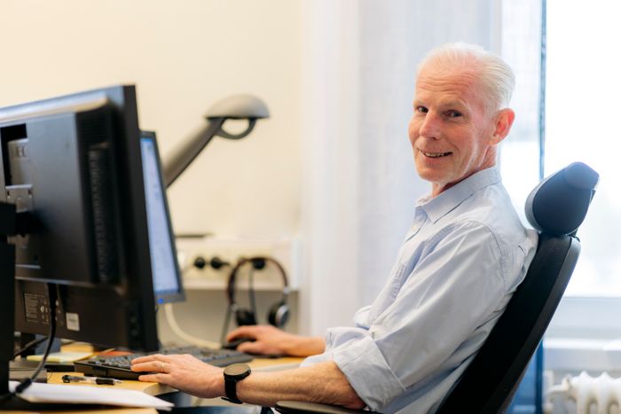 Jan sitter vid en dator och tittar in i kameran.