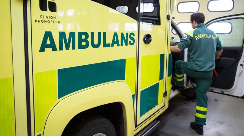 En medarbetare i gröna ambulanskläder kliver in i passagerarsätet på en ambulans.