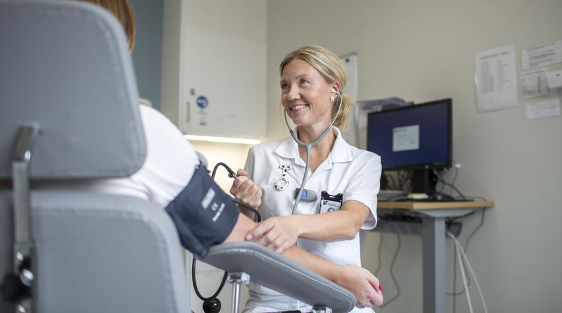 Undersköterska tar blocktrycket på en patient.