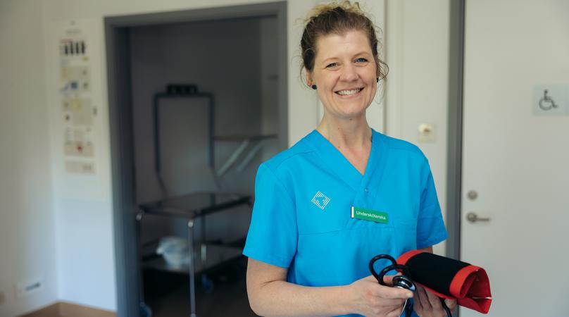 En undersköterska håller i en blodtrycksmätare.