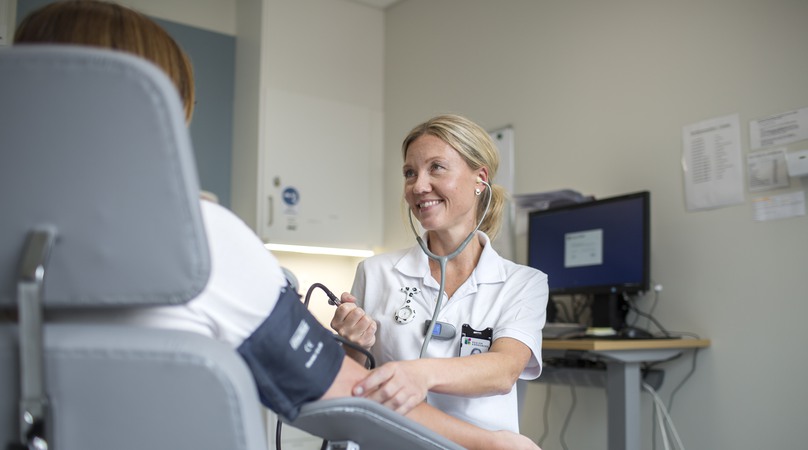 Undersköterska tar blocktrycket på en patient.