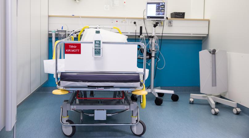 En vårdsäng med medicinsk utrustning står i ett vårdutrymme.