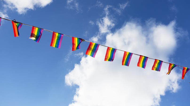 Pride-flaggor mot bl&aring; himmel.