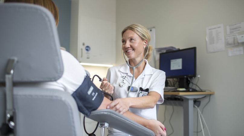 Undersköterska tar blocktrycket på en patient.
